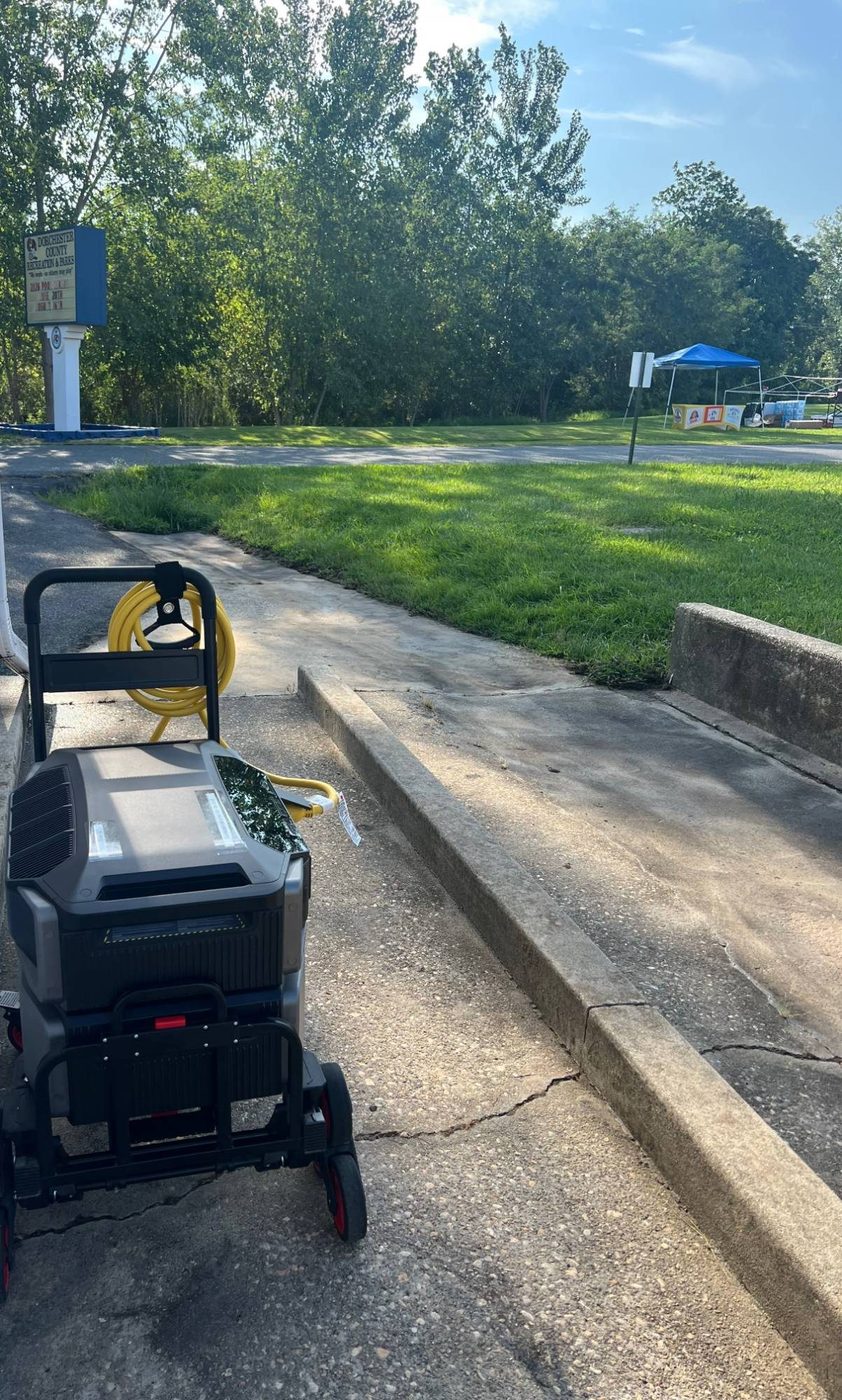 EcoFlow rig with a coiled heavy-duty cable on a wheeled cart, parked on a park sidewalk with vendor tents visible in the distance