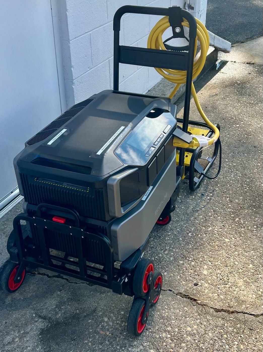 Close-up of the EcoFlow DELTA Pro Ultra inverter and battery on the wheeled cart, plugged into the Champion Pro power distribution unit via a yellow heavy-duty cable